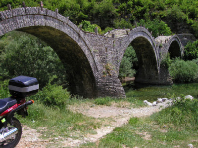 Motorrad vor Bogenbrücke aus Stein bei Monodendri