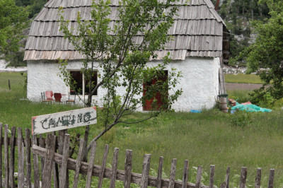 Altes Haus am Wegesrand mit Schild Camping im Vordergrund