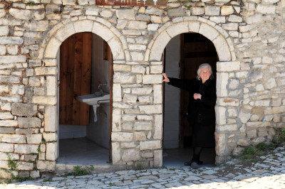 Frau blickt aus einer öffentlichen Toilette im inneren Bereich der Burg