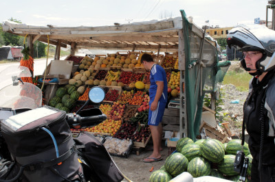Verkaufsstand mit Obst und Motorradfahrer am Straßenrand