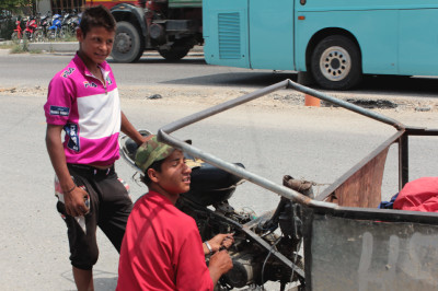 Zwei junge Moppedfahrer reparieren am Straßenrand ein Mofa