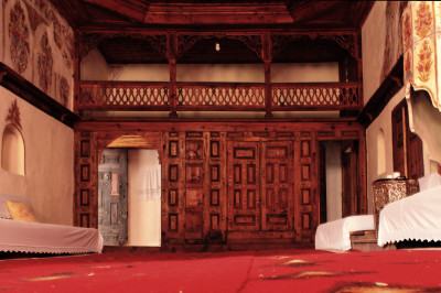 Zimmer im Zekati-Haus mit rotem Teppich und Holzvertäfelungen.
