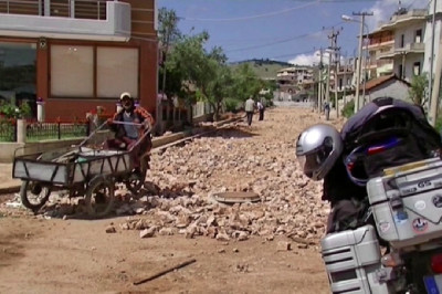 Einfahrt in einen Baustelle mit Motorrad und Karren in Ksamil.