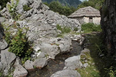 Idylischer Flusslauf mit Steinhaus im Hintergrund