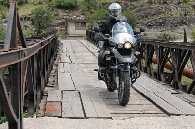 Motorrad fährt über eine mit Holzbrettern ausgelegte Brücke