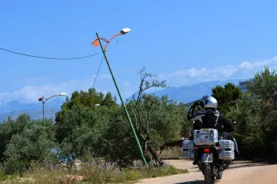Auf dem Weg nach Ksamil Motorrad mit Beifahrer auf Strasse mit geknickter Straßenlaterne