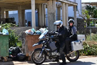 Aufgeräumt - immerhin liegt der Müll im Container. Der meiste zumindest. Motorradfahrer mit Beifahrerin vor Müllcontainer