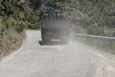 Nach Bulqizë werden die Berge höher und die Straße schlängelt sich kurvig an einem Berghang entlang. Aber auch einige LKWs. Bergbau LKW in Staubwolke auf dem Weg nach Bulqize.