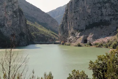 Der Mat wird als Shkopet-Stausee über viele Kilometer in einem schmalen Tal angestaut und die Straße folgt dem Tal. Mat Stausee mit Staumauer in der Ferne umrahmt von Bergen.