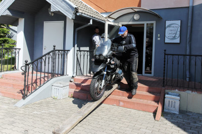 Mann schiebt Motorrad über Treppenstufen