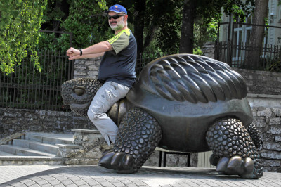 Mann sitzend auf bronzener Schildkröte