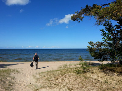 Mann läuft auf Sandweg dem Meer entgegen
