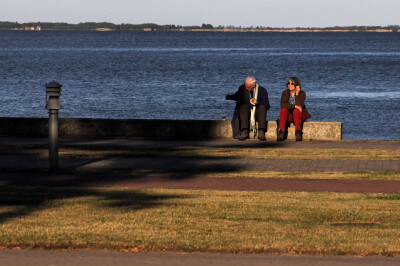 Zwei Personen sitzen an Hafenpromenade von Juodkrante