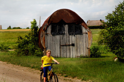 Junge auf Fahrrad vor Holzhütte