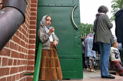 Kleines Mädchen steht vor grüner Tür des Klosters Pühtitsa.