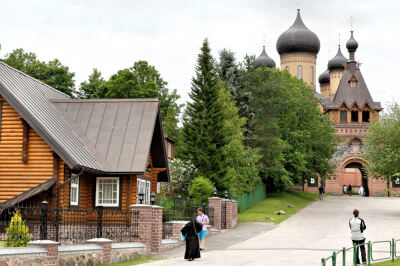 Aufgang zum Kloster Pühtitsa. Links ein Mönch und im Hintergrund das Kloster.