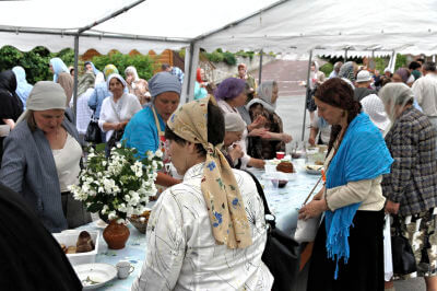 Viele Menschen um überdachte Tische mit Essen bei einer Feier beim Kloster