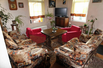 Wohnzimmer mit zwei roten Sessel und Fernseher im Gasthaus am Peipussee