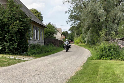 Motorrad fährt auf Landstraße an einem Haus vorbei