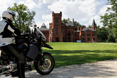 Motorradfahrer steht vor dem Schloss Sangaste