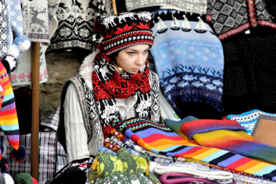 Mädchen mit Mütze sitzt im Verkaufsstand für Handarbeisartikel in der Altstadt von Tallinn