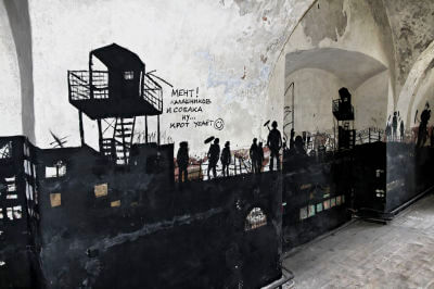 Gefängniskomplex mit Häftlingen als schwarzes Graffiti auf weißer Wand im Gefängnis Patarei