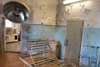 Verrostetes Eisenbett ohne Matratze im verfallenen Medizinraum des Gefängnis Patarei