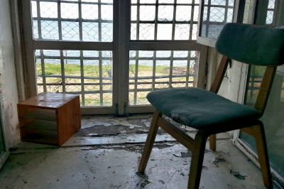 Stuhl vor vergitterten Fenster im Gefängnis Patarei