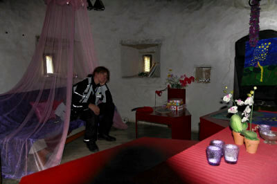 Frau sitzt auf Bett mit Baldachin im Rapunzelzimmer im Wohnturm Kiiu