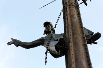 Bronzeskulptur eines Telefontechnikers an einem Mast hängend