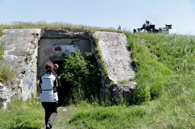 Frau geht auf grasbewachsenen Bunker in Liepaja zu