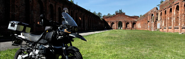 Motorrad steht innerhalb eines Backsteingebäudes ohne Dach - der sogenannten Manege in Liepaja
