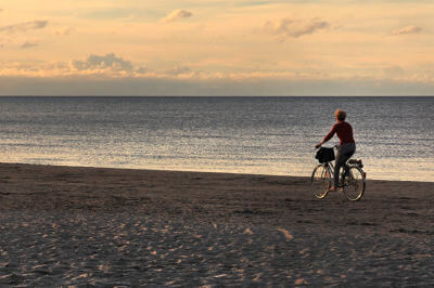 Fahrradfahrerin fährt am Strand