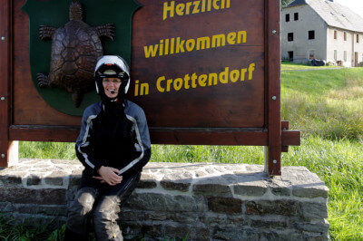 Motorradfahrerin vor Herzlich Willkommen Schild in Crottendorf