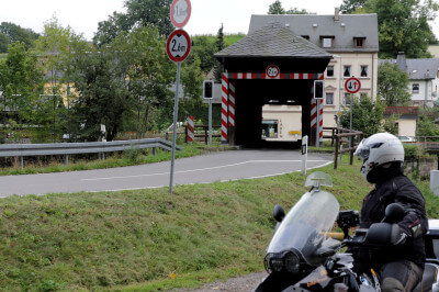 Motorrad steht vor gedeckter Holzbrücke über die Zschopau