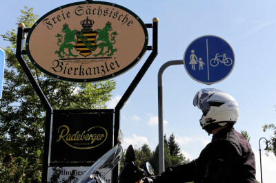 Motorradfahrer steht vor Schild zur Freien Sächsischen Bierkanzlei
