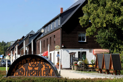 Haus in Johanngeorgenstadt mit Schwibbogen aus Metall im Vordergrund