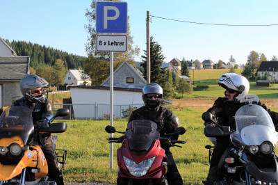 Drei Motorräder stehen vor Parplatzschild in Kühnhaide