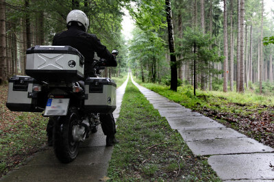 Motorrad steht auf teilweise betoniertem Waldweg
