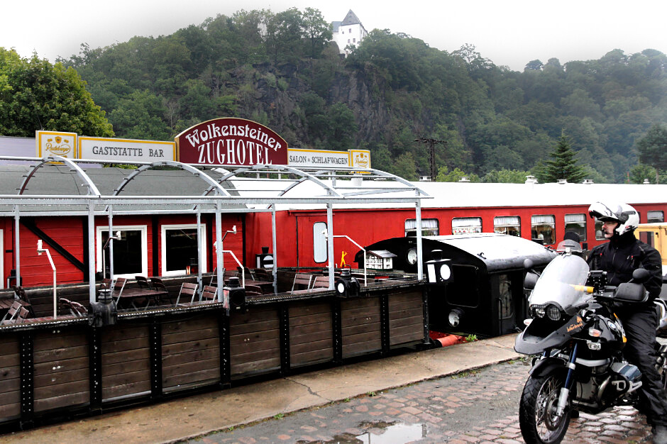 Motorrad mit Fahrer steht rechts am Eingang zum Zughotel in Wolkenstein