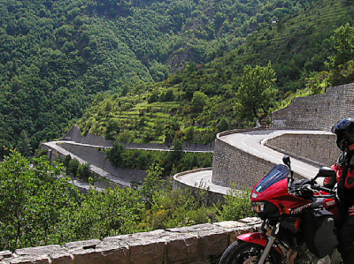 Motorradfahrer steht an den Serpentinen des Col de Turini