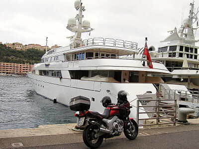 Motorrad steht vor einer privaten Yacht im Hafen von Monaco