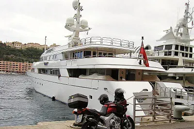 Kleines Bötchen im Hafen von Monaco Motorrad steht vor einer privaten Yacht im Hafen von Monaco