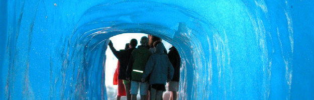 Personen laufen durch einen Eistunnel im Rhone-Gletschers