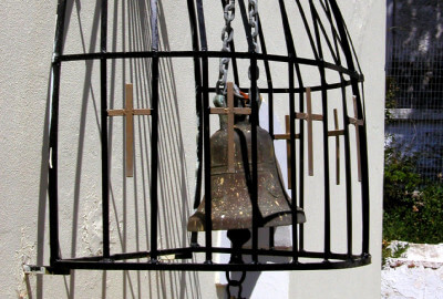 Glocke hinter schwarzem Gitter aus Stahl mit Kreuzen verziert im Kloster Kathara