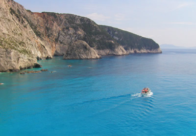 Boot schippert entlang der Felsenküste von Lefkada.