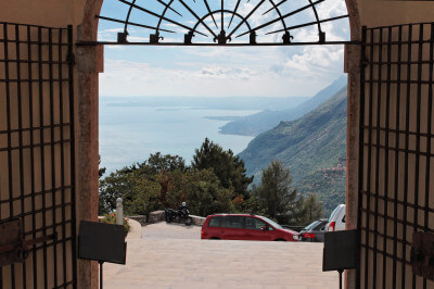 Blick aus geöffnetem Tor auf den Gardasee von der Kirche Madonna di Monte Castelloaus