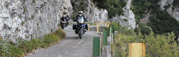 Mehrere Motorradfahrer fahren auf der schmalen Straße über den Passo del Spina