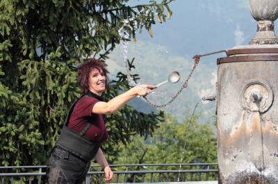 Frau mit Suppenkelle vor Brunnen in Avenone