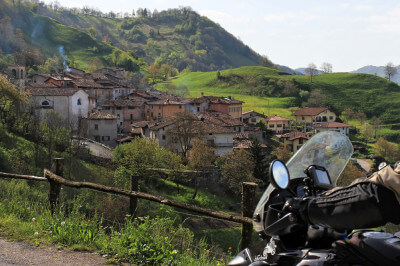 Motorradfahrer und im Hintergrund ein typisches Dorf für die Gegend am Idrosee